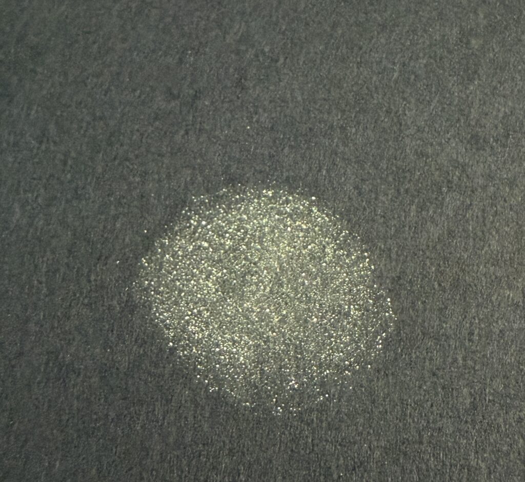 エレガンス プレジール アイズ13を紙に塗ったスウォッチ。上品に輝くイエローグリーンの色味。